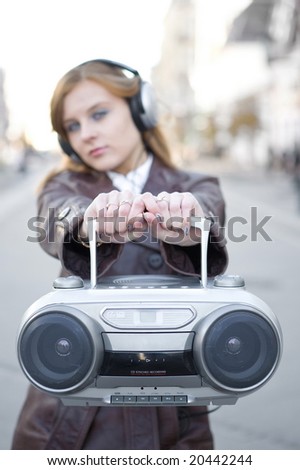 Pretty girl with MP3 stereo system on the street background