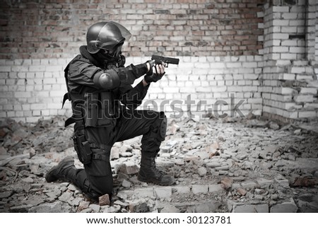 Armed man in protective cask with a pistol on the ruined building background.