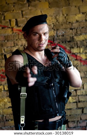 Armed mercenary with \'Kalashnikov\' submachine gun on the yellow wall background