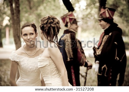 Two pretty woman dressed in vintage dress and accessories are discussing hussars. Focus point on the girls.