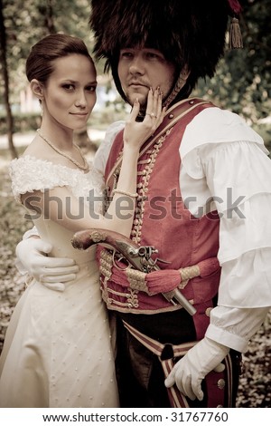 Russian hussar in vintage outfit with pretty bride. Retro-styled photo.