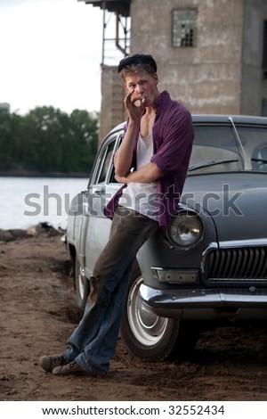 Smoking taxi driver near the vintage car.