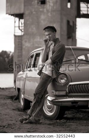 Smoking taxi driver near the vintage car. Retro-styled photo.