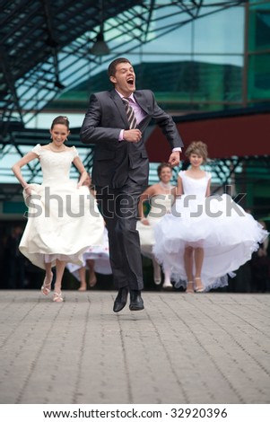 Laughing groom is escaping from the crowd of brides.