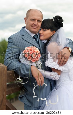 Portrait of a newlywed couple with the bride\'s bouquet. Bride is dreaming on the groom\'s shoulder.