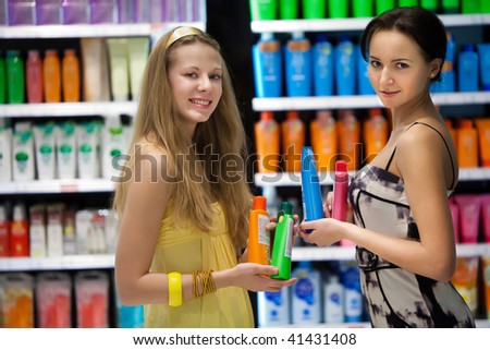 Pretty girls in the shop with a cosmetics. Blurred colorful showcases on the background.