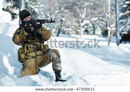 Russian soldier in winter uniform with the Kalashnikov machine gun on the forest background.