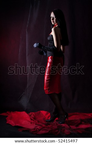 Beautiful woman in the dark room touching a decorative net.