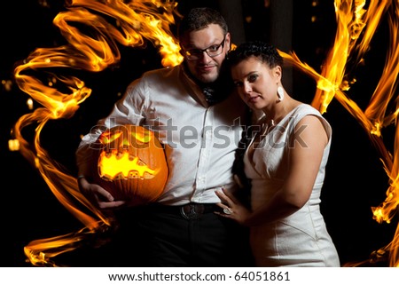 Pretty couple with the pumpkin surrounded by fire flames