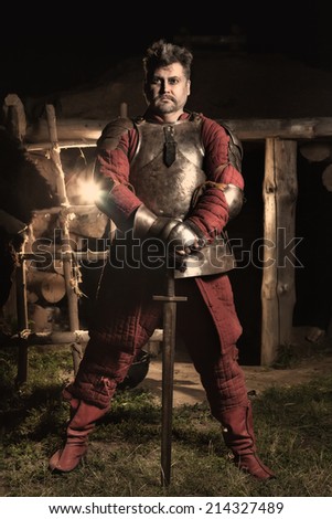 Medieval knight. Wooden house on the background.