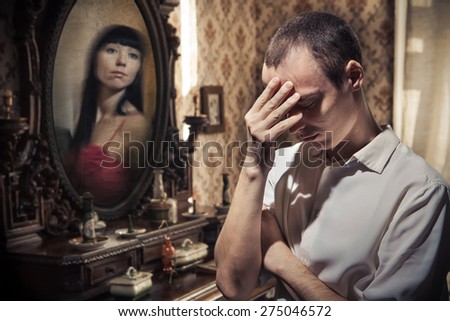 Man in grief on the vintage mirror background. The reflection of his woman on the background.