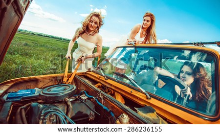 Beautiful women with tools are repairing a car on the rural road