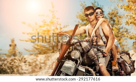 Sexy couple of bikers with guns on the summer background.