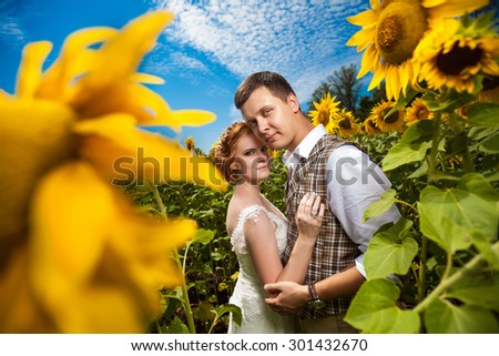 Happy embracing couple on the sunflowers field background.