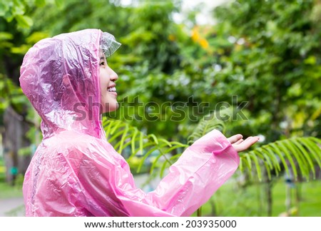 Asian woman in pink raincoat checking for rain in the garden