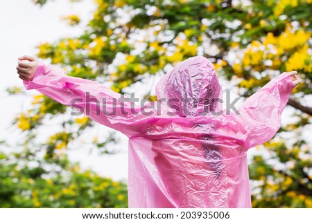 Asian woman in pink raincoat enjoying the rain in the garden