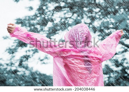 Asian woman in pink raincoat enjoying the rain
