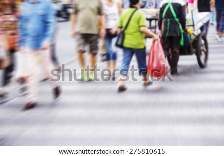 Abstract people are crossing road at the crosswalk. Blurred background.