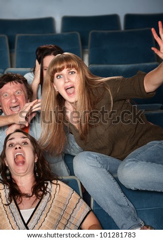Scared Caucasian teen jumps out of her seat in theater