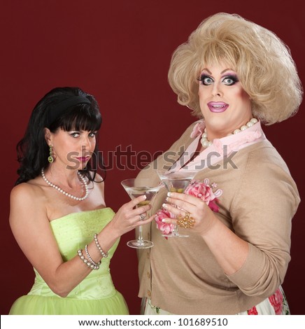 Happy drag queen with suspicious woman toast martinis