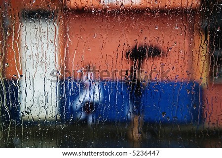 Rain on a window looking out to people in a street scene.