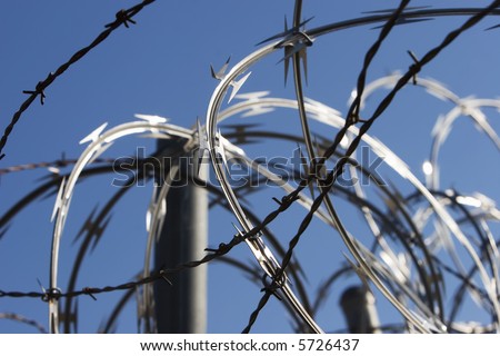 Razor and barbed wire on top of a fence.