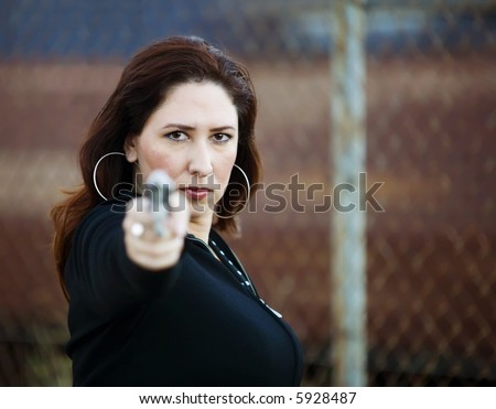 Hispanic woman behind a wall holding a handgun in ready to fire position.