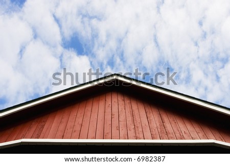 Red barn-style roof against a sky with soft clouds.