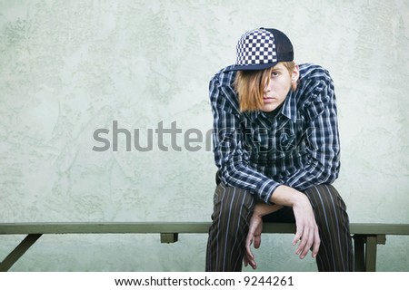 Teenage boy with crazy hair and a clothes on a green bench.