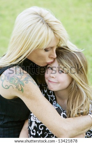 Pretty mom hugs and kisses her cute freckle-faced daughter
