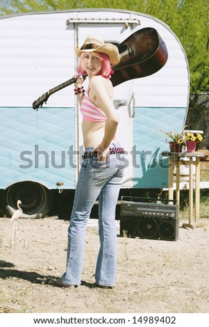 stock photo Pretty Woman Front of Vintage Travel Trailer with a Guitar