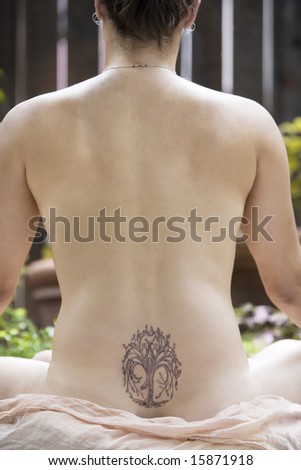 stock photo : Back of a nude woman with a Yoga tattoo meditating