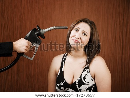Woman with a gas nozzle pointed like a gun to her head