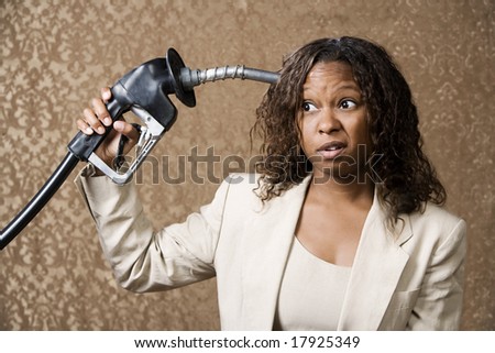 Woman holding gas nozzle like a gun to her head