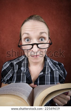 Woman with big eyes and glasses reading a book.