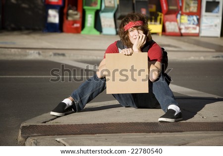 Young Man on Street Corner with Blank Cardboard Sign