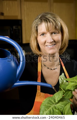 Woman in Kitchen Watering Wearing Apron a Plant