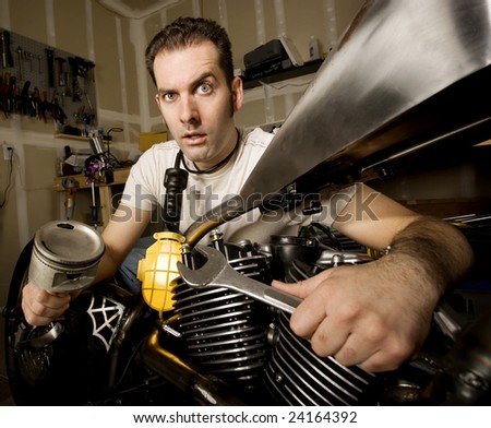 Overwhelmed man in residential garage working on chopper-style motorcycle