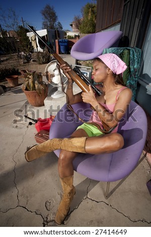 Black woman kissing rifle in front of house with messy yard