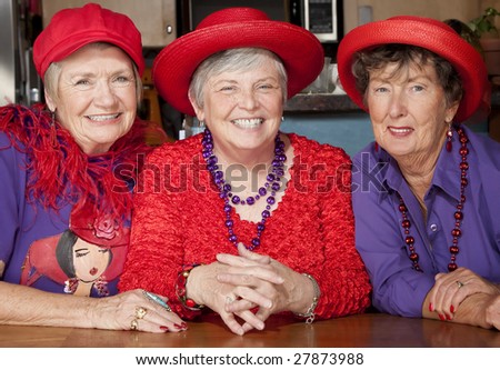 Three friendly senior women wearing red hats