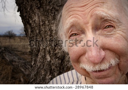 Portrait of senior man outdoors in front of tree