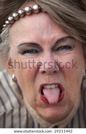 Closeup of rude old woman sticking out her tongue