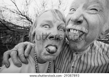 Closeup portrait of crazy elderly couple outdoors sticking out tongues
