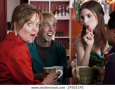 Four friends having an animated discussion in a coffee house