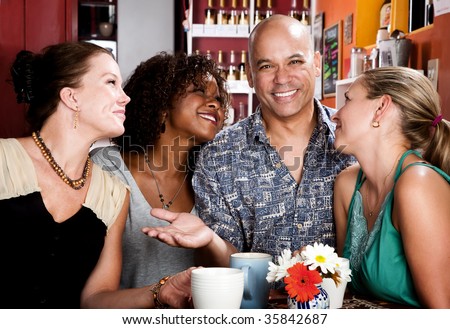 Man with shaved head and three pretty women in coffee house
