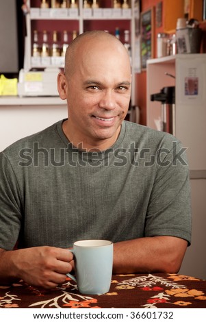 Handsome man with shaved head in cafe with cup
