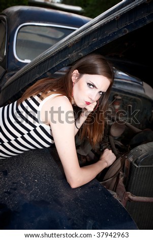 Pretty girl with engine failure on vintage sedan