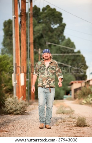 Rugged man in camoflauge walking on dirt road