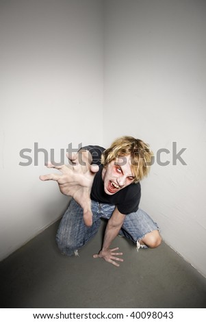 Young blonde male zombie reaching towards the camera