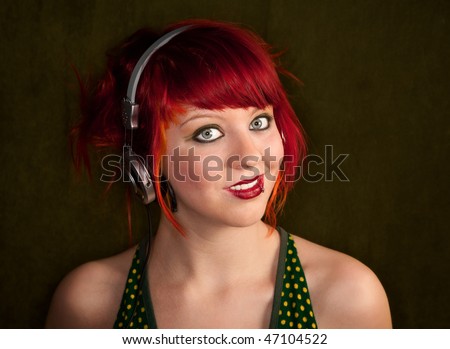 Pretty punk girl with brightly dyed red hair listening to music